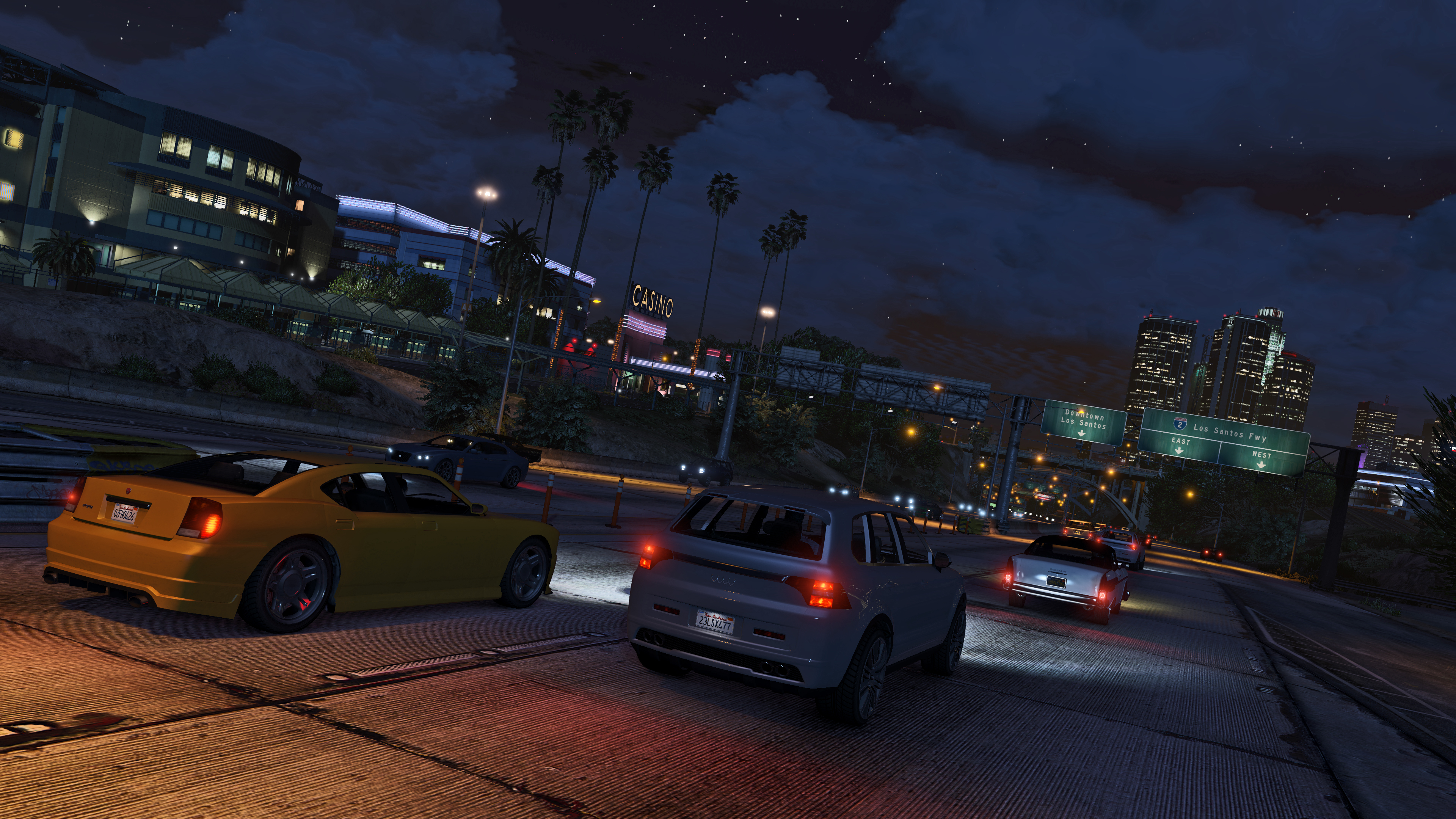 Cars driving toward downtown Los Santos at night in Grand Theft Auto V